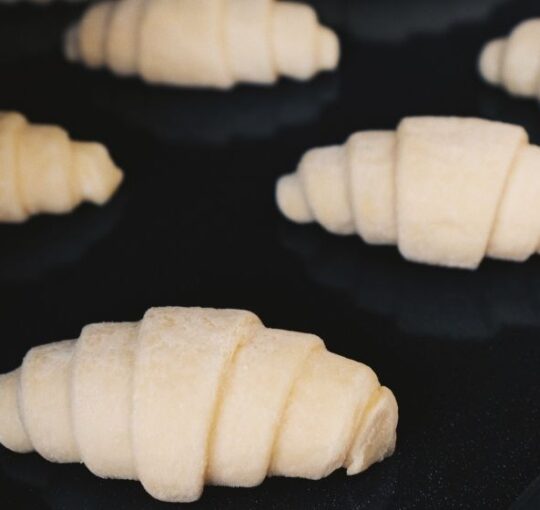 foto de vários pães crus prontos para serem assados e fundo preto